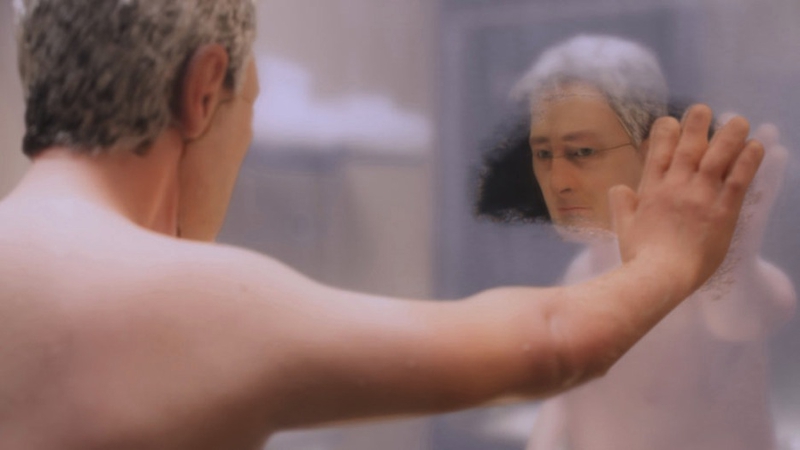Michael wipes away the steam to see his own face in the mirror.